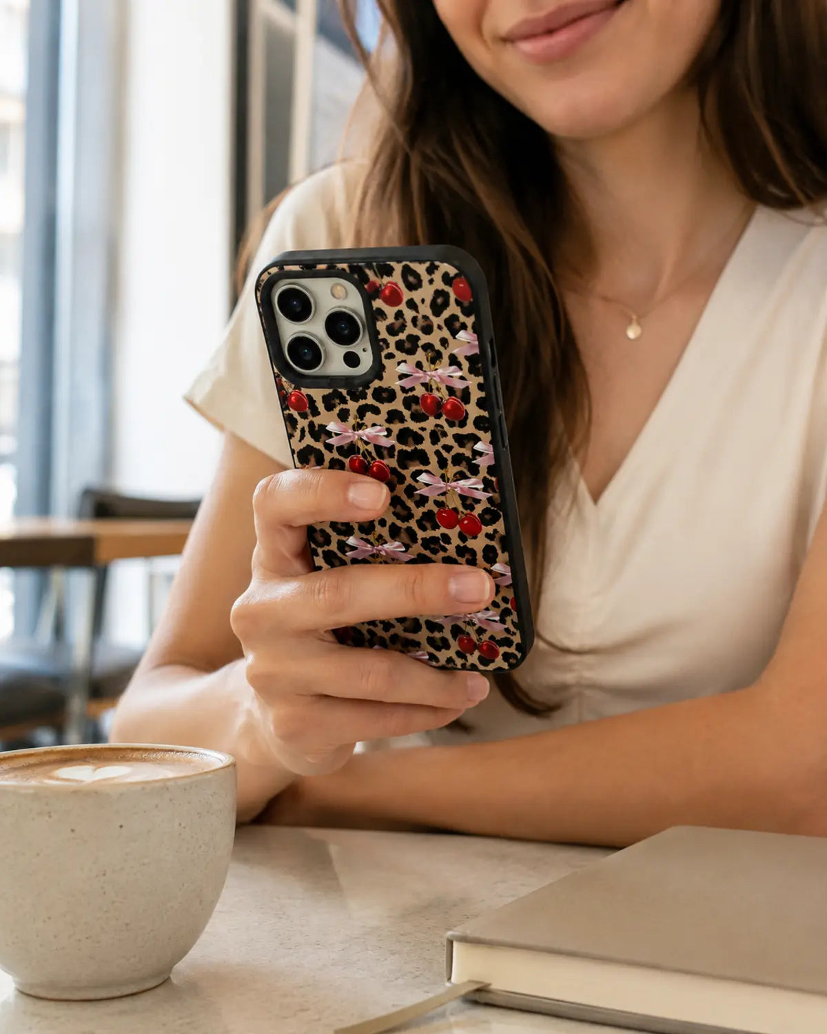 Woman holding an Ehreus cherry leopard black bumper case in a café
